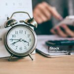 Persona consulta documenti accanto a sveglia e calendario con data cerchiata, a rappresentare i tempi di conservazione dei dati CRIF