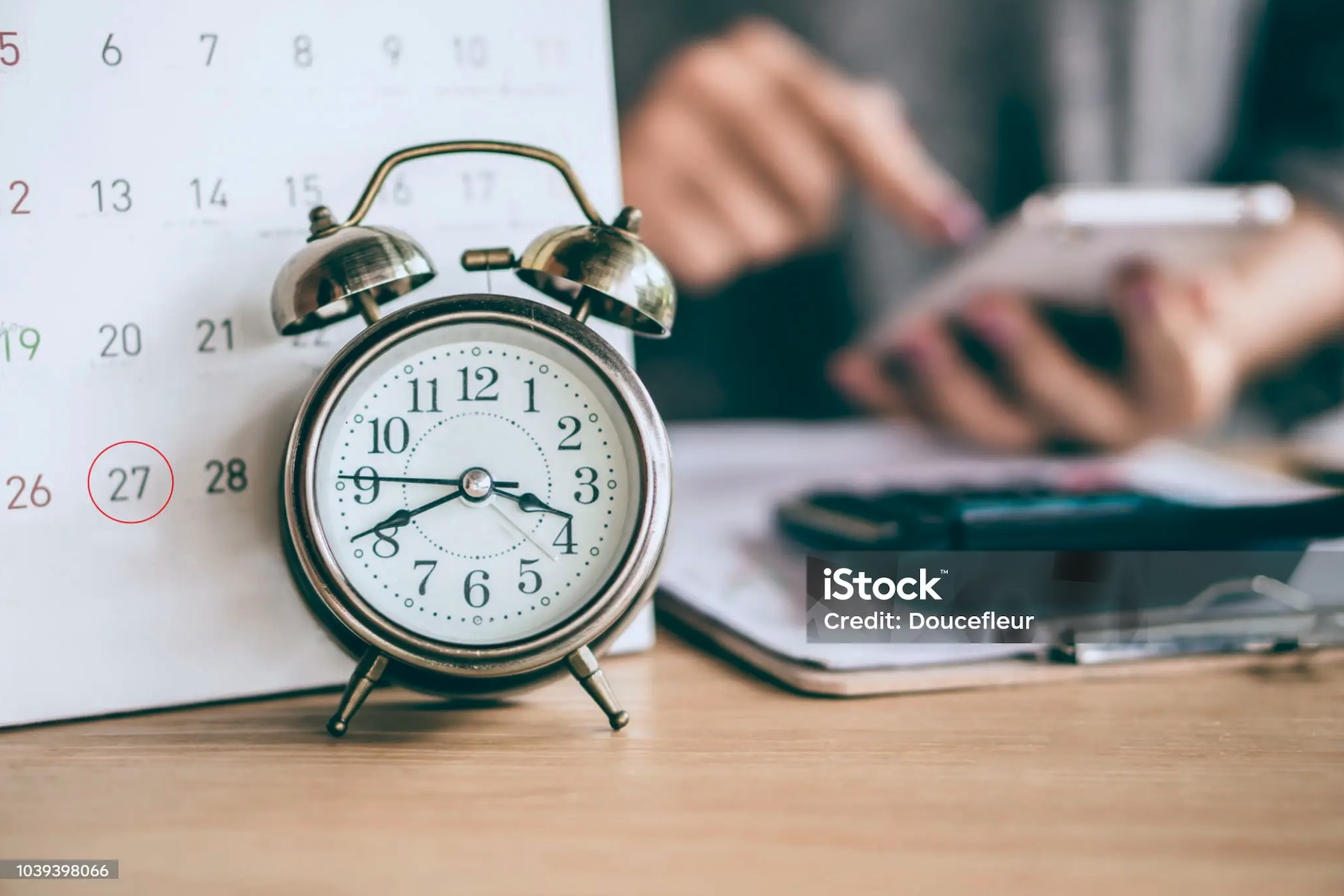 Persona consulta documenti accanto a sveglia e calendario con data cerchiata, a rappresentare i tempi di conservazione dei dati CRIF