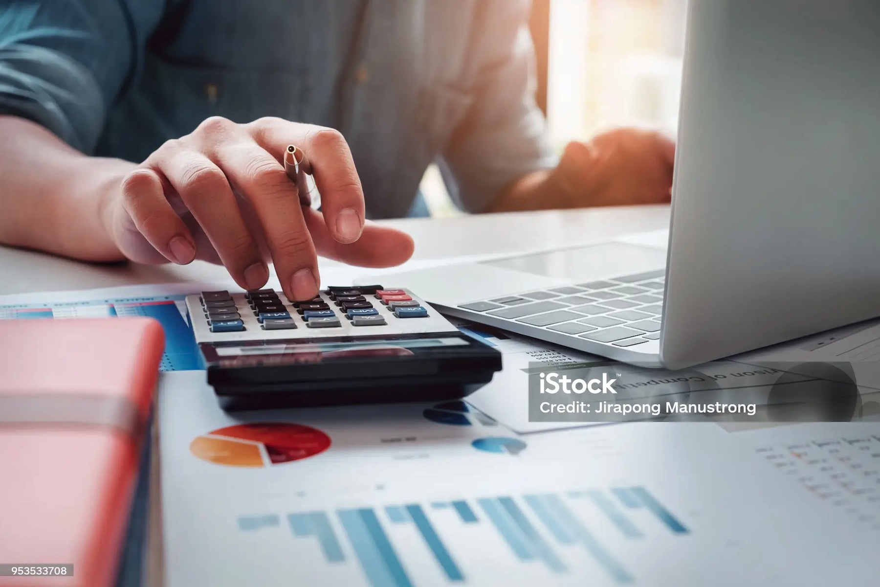 Persona che utilizza una calcolatrice accanto a documenti finanziari per valutare i costi di un prestito